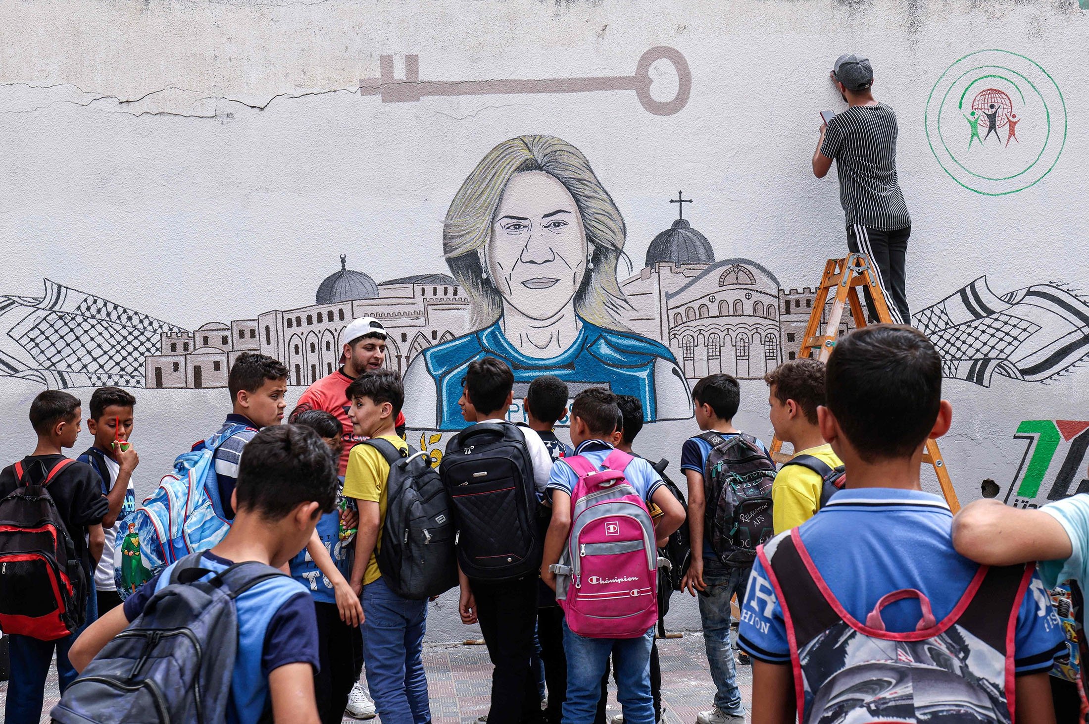 Okul çocukları, Filistinli sanatçıların, Gazze Şeridi'nin güneyindeki Khan Younis, Filistin'de öldürülen kıdemli El Cezire gazetecisi Shireen Abu Akleh'i onurlandıran bir duvar resmi boyamasını izliyor, 14 Mayıs 2022. (AFP Fotoğrafı)