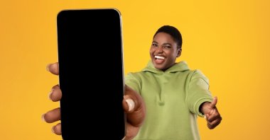 A happy woman holding a cellphone. (Shutterstock Photo)