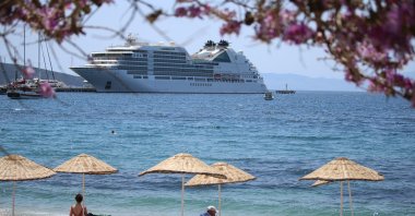 The Bahamas-flagged cruise ship Seabourn Encore anchors off the coast in Bodrum as people enjoy seaside, Muğla, southwestern Turkey, May 11, 2022. (AA Photo)