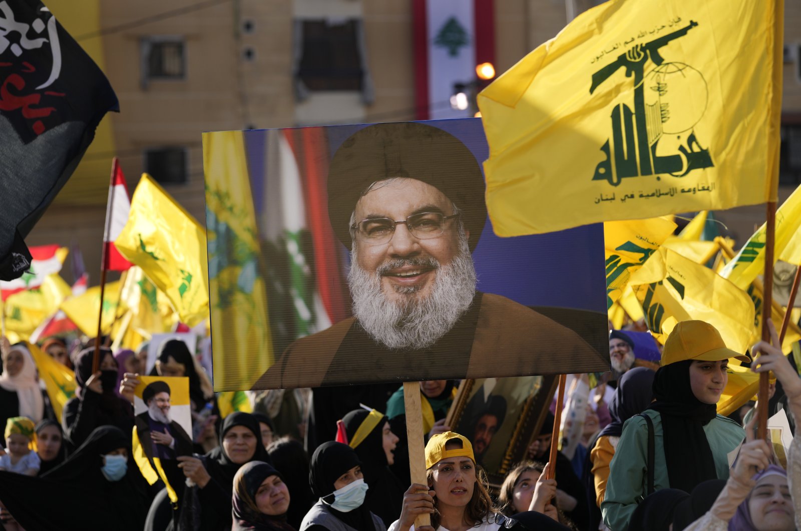 Hezbollah supporters wave portraits of Hezbollah leader Sayyed Hassan Nasrallah and their group flags, during an election campaign, in the southern suburb of Beirut, Lebanon, May 10, 2022. (AP Photo)