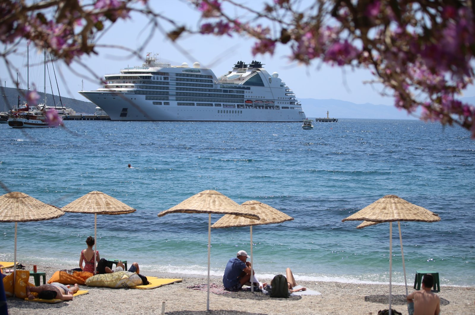 The Bahamas-flagged cruise ship Seabourn Encore anchors off the coast in Bodrum as people enjoy seaside, Muğla, southwestern Turkey, May 11, 2022. (AA Photo)