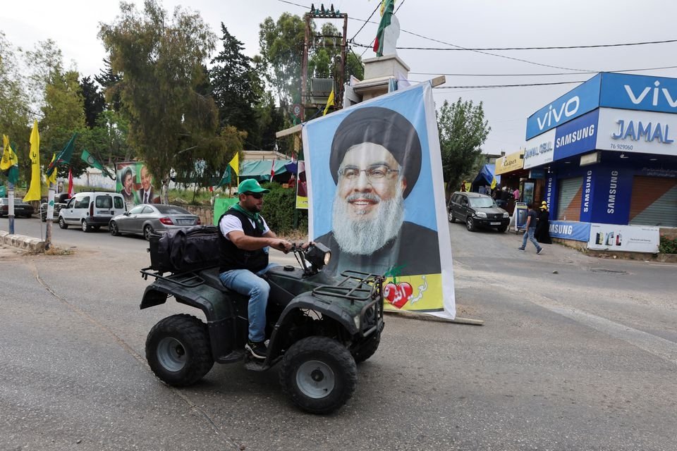 A supporter of the Shiite Amal Movement drives past a poster of Lebanon&#039;s Hezbollah leader Sayyed Hassan Nasrallah on the day of parliamentary elections, in Houla, southern Lebanon May 15, 2022. (Reuters Photo)