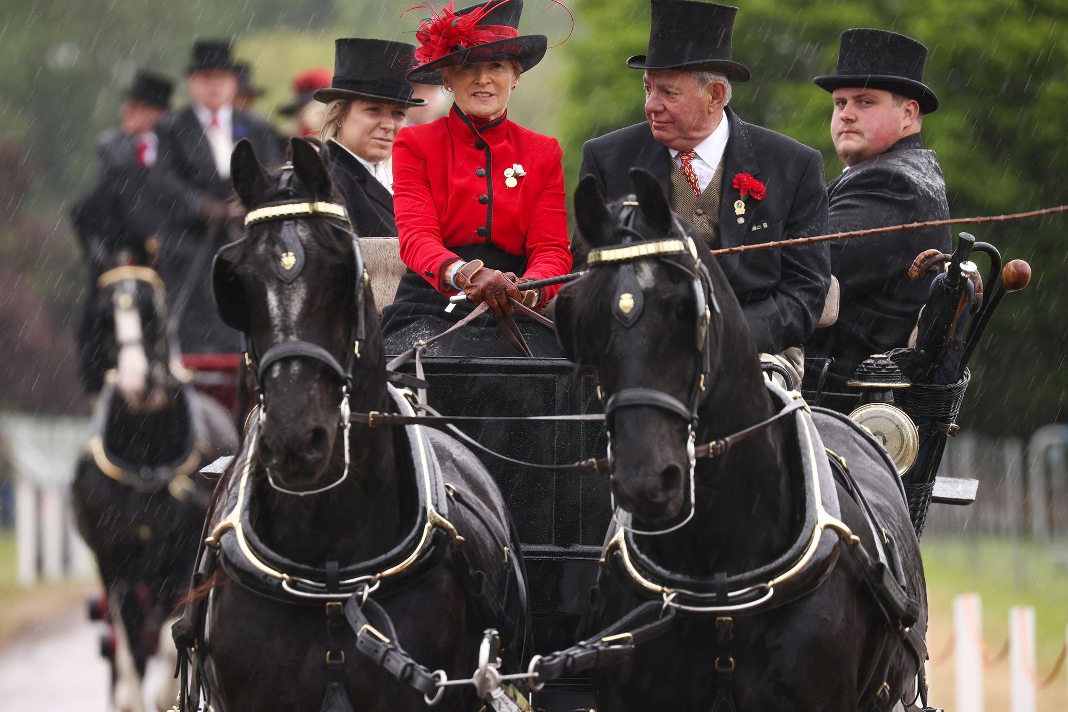 Anggota British Driving Society naik kereta kuda saat hujan deras selama Royal Windsor Horse Show di Windsor, Inggris, 15 Mei 2022. (Foto Reuters)