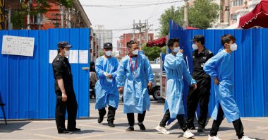 Workers in protective suits walk through the gate of a barricaded residential area under lockdown amid the COVID-19 outbreak, Beijing, China, May 17, 2022. (Reuters Photo)