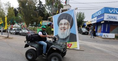 A supporter of the Shiite Amal Movement drives past a poster of Lebanon&#039;s Hezbollah leader Sayyed Hassan Nasrallah on the day of parliamentary elections, in Houla, southern Lebanon May 15, 2022. (Reuters Photo)