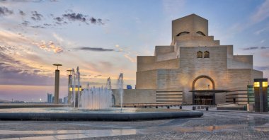 Doha,Qatar-April 28,2013 :Museum of Islamic Art , Doha,Qatar in daylight exterior view with fountain in foreground and clouds in the sky in the background