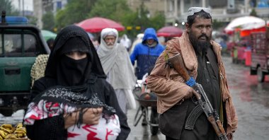A Taliban fighter stands guard as people walk through the old market, in the city of Kabul, Afghanistan, Tuesday, May 3, 2022. (AP Photo)