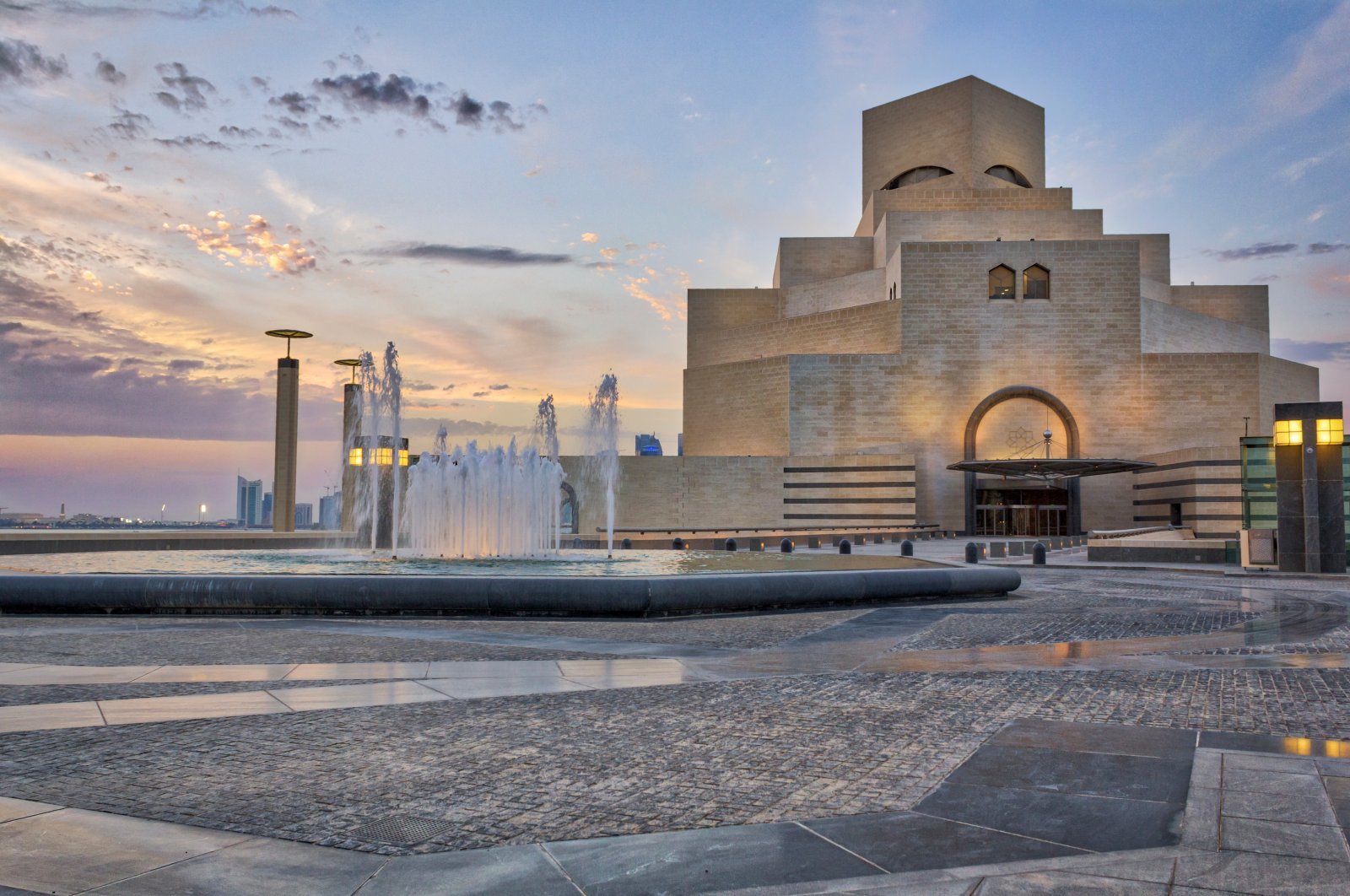 Doha,Qatar-April 28,2013 :Museum of Islamic Art , Doha,Qatar in daylight exterior view with fountain in foreground and clouds in the sky in the background