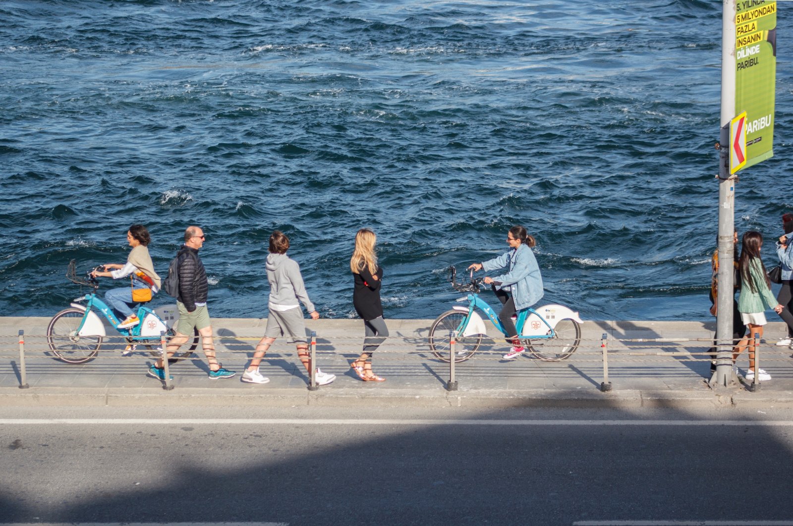 Young people ride bikes and walk near the Bosporus, in Istanbul, Turkey, May 7, 2022. (Shutterstock Photo)