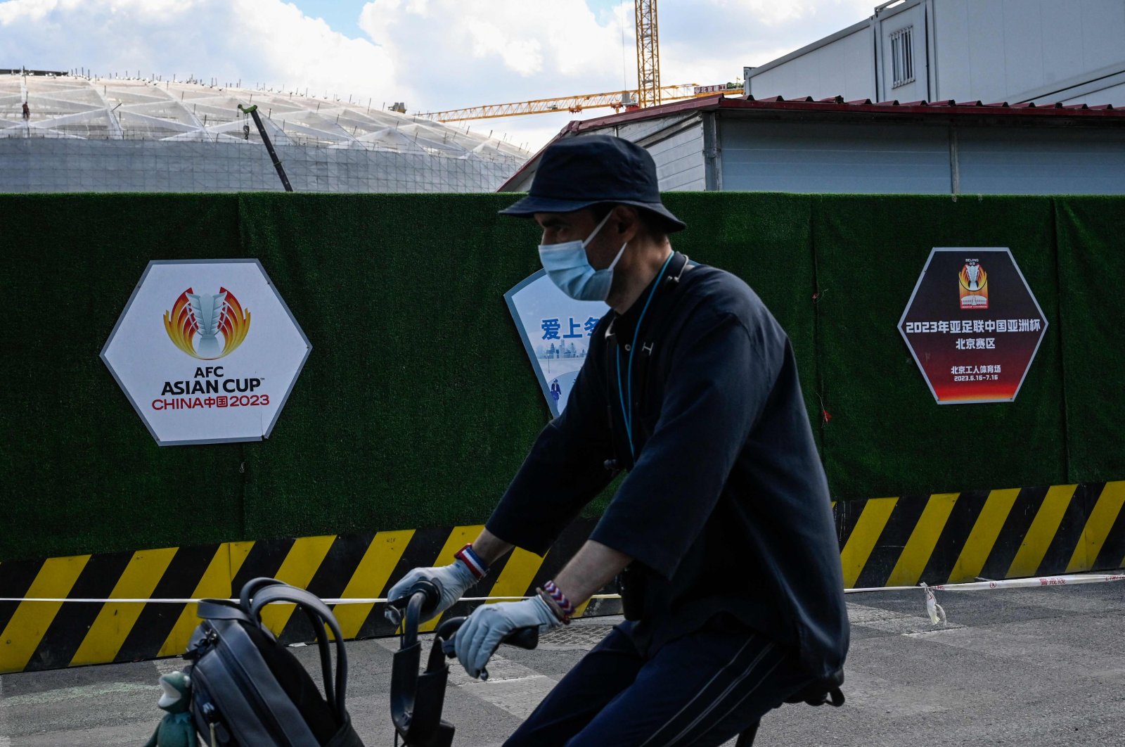 A man cycles past the construction site of the Workers&#039; Stadium, a planned venue for the 2023 Asian Cup, Beijing, China, May 14, 2022. (AFP Photo)