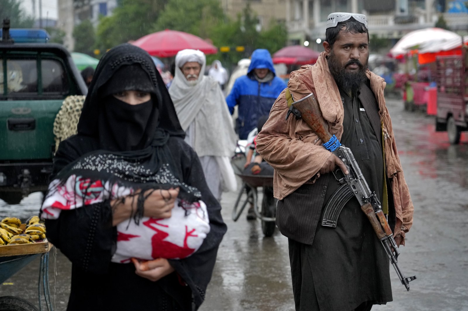 A Taliban fighter stands guard as people walk through the old market, in the city of Kabul, Afghanistan, Tuesday, May 3, 2022. (AP Photo)