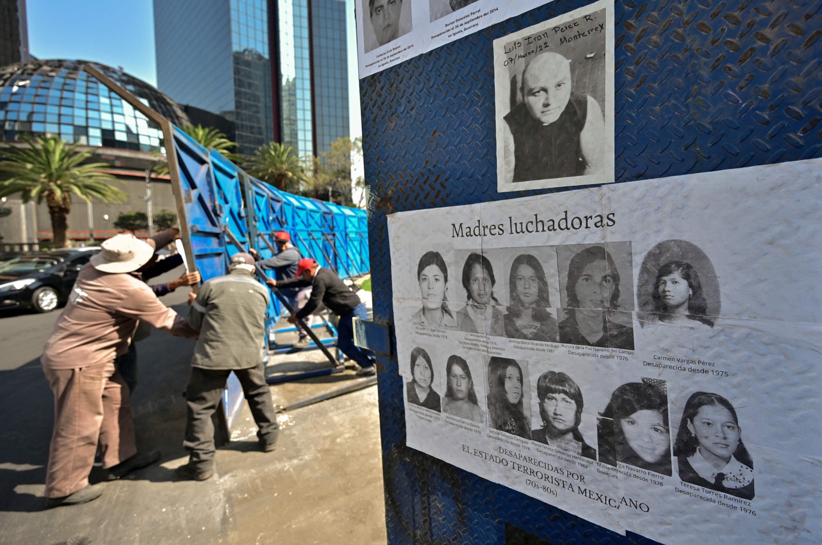 Mexico City government workers move a fence with photos of missing persons from a roundabout on Paseos de la Reforma Avenue after relatives and members of search groups proposed to rename it &quot;Glorieta de Las y Los Desaparecidos&quot; (Roundabout of the Disappeared), in Mexico City, Mexico, May 17, 2022. (AFP Photo)