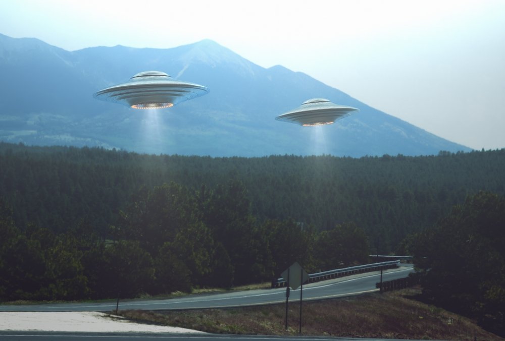 Illustration of two UFOs hovering over a road. (Shutterstock Photo)