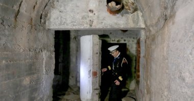 Capt. Eduart Jeminaj opens one of the gates to the tunnel of the base near the city of Himara, Albania, April 27, 2022. (AFP Photo)