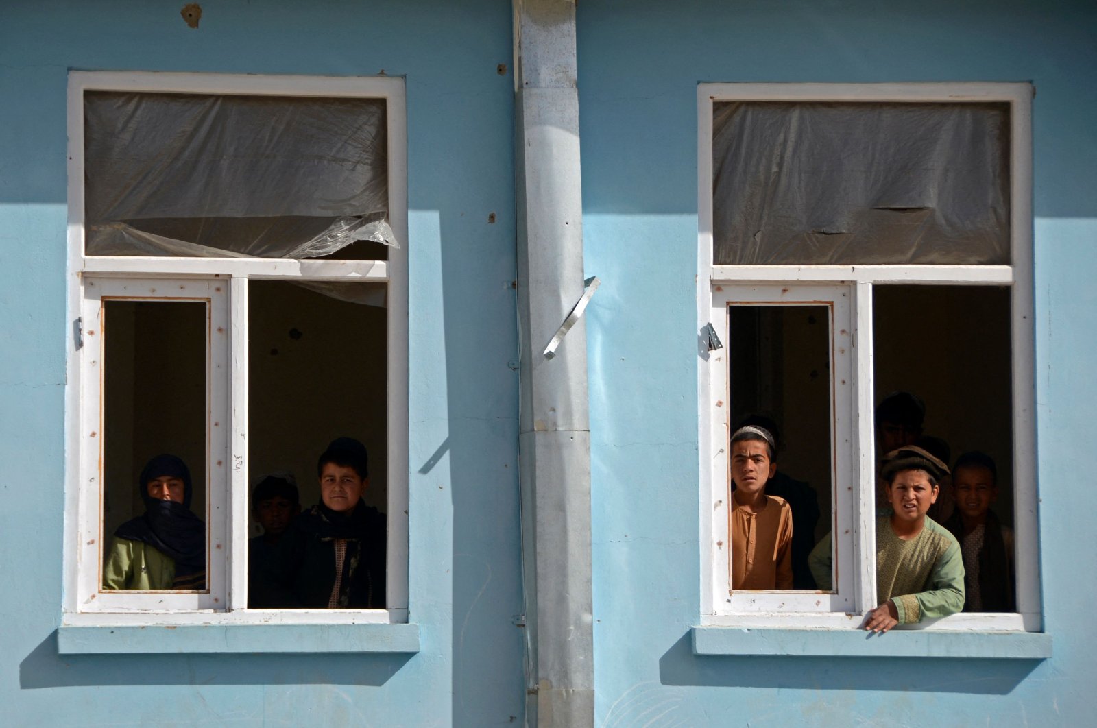 Boys look out from the window sill of a school that was damaged during the conflict between the Taliban and Afghanistan&#039;s former ruling government, Kandahar, Afghanistan, May 12, 2022. (AFP Photo)