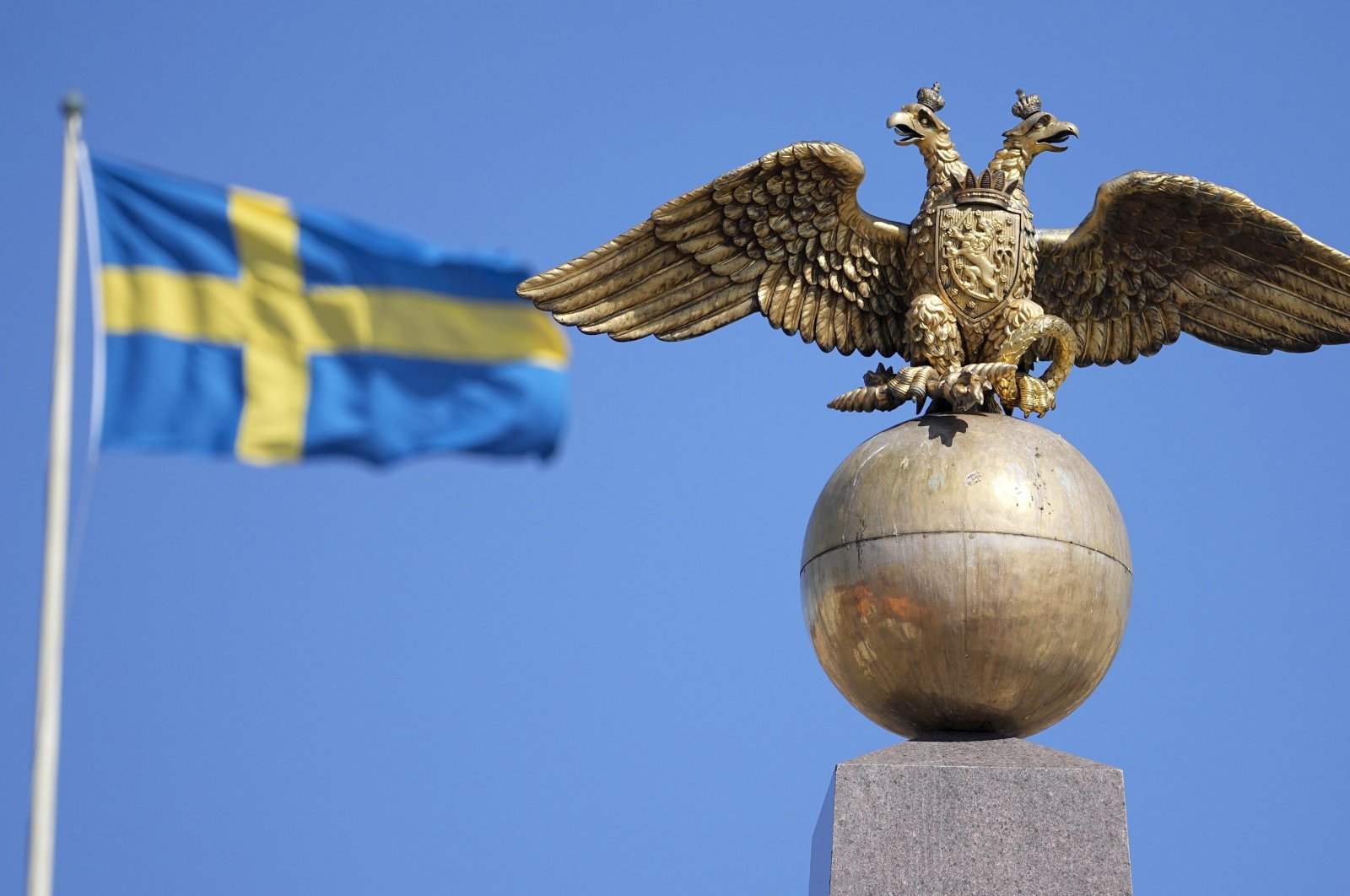 A Russian imperial double-headed eagle is seen in front of a Swedish flag on the Czarina&#039;s Stone in the Market Square, in Helsinki, Finland, May 13, 2022. (AP Photo)