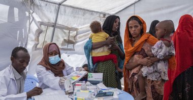 In this photo released by UNICEF, a mobile health and nutrition team attends to displaced mothers and their children at the Guyah site for internally displaced people in the Afar region of Ethiopia, May 10, 2022. (UNICEF via AP)