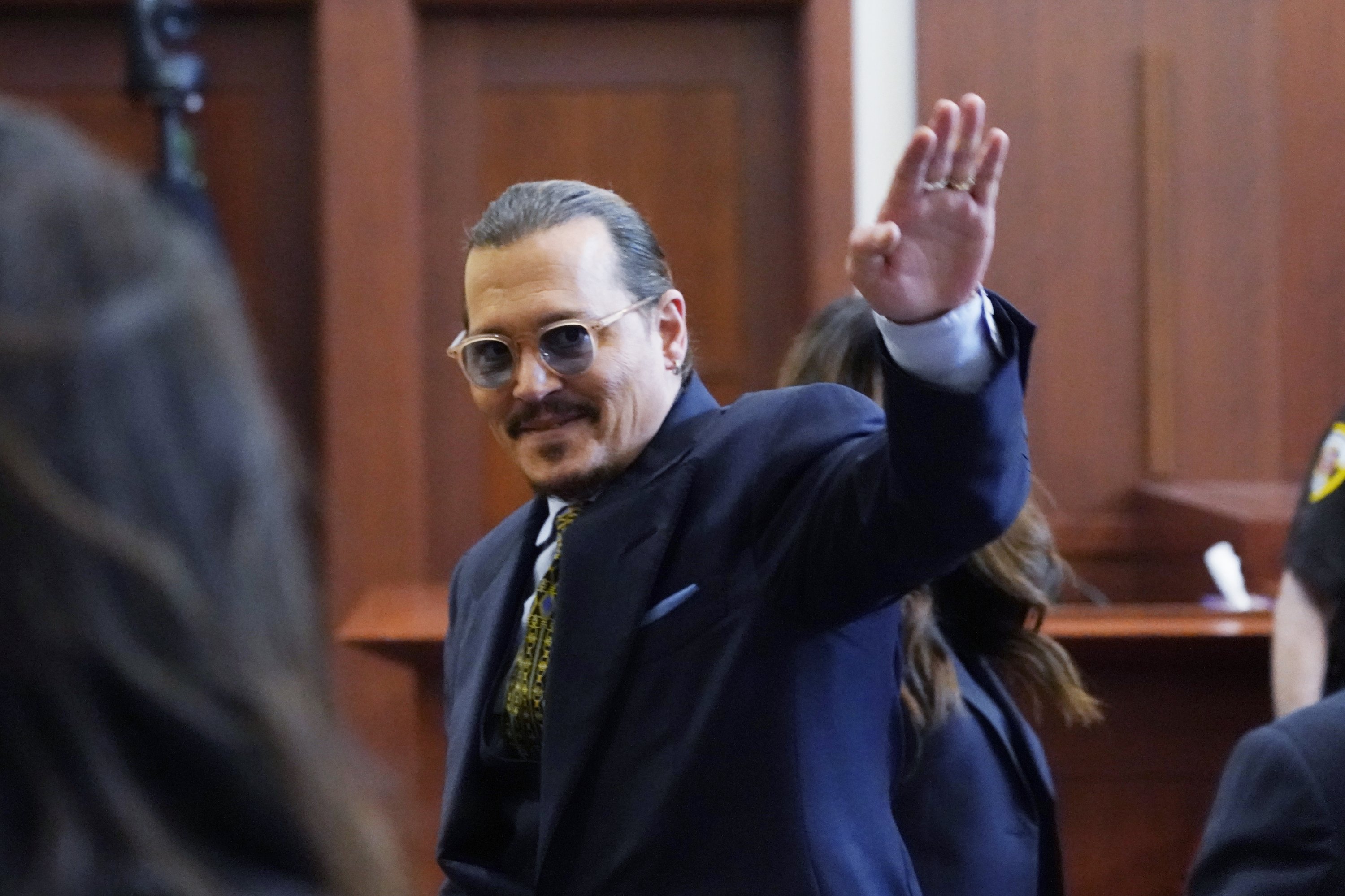 Actor Johnny Depp gestures to the gallery in the courtroom as he leaves for the day at the Fairfax County Circuit Courthouse in Fairfax, Virginia, US, May 23, 2022. (AP)