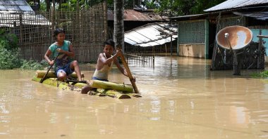 Children ride a bamboo raft through a flooded area after heavy rains in Morigaon district of Assam state, India, May 22, 2022. (AFP Photo)
