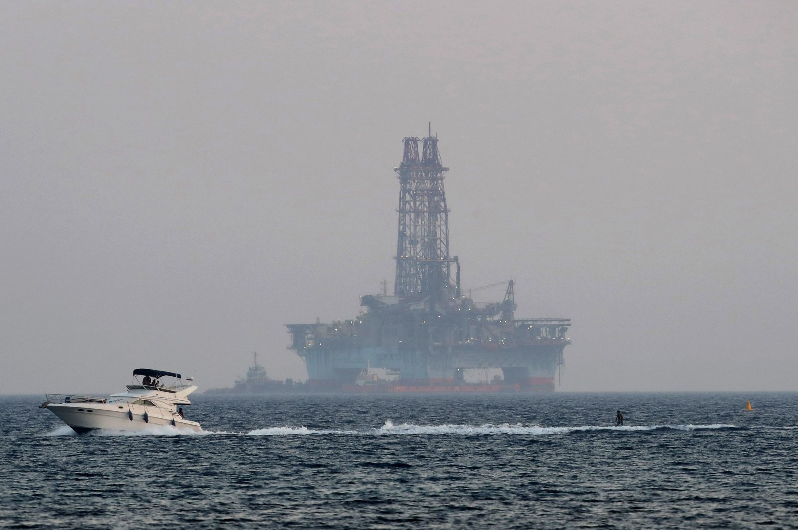 An offshore drilling rig is seen off Cyprus&#039; coastal city of Limassol as a boat passes with a skier, July 5, 2020. (AP Photo)