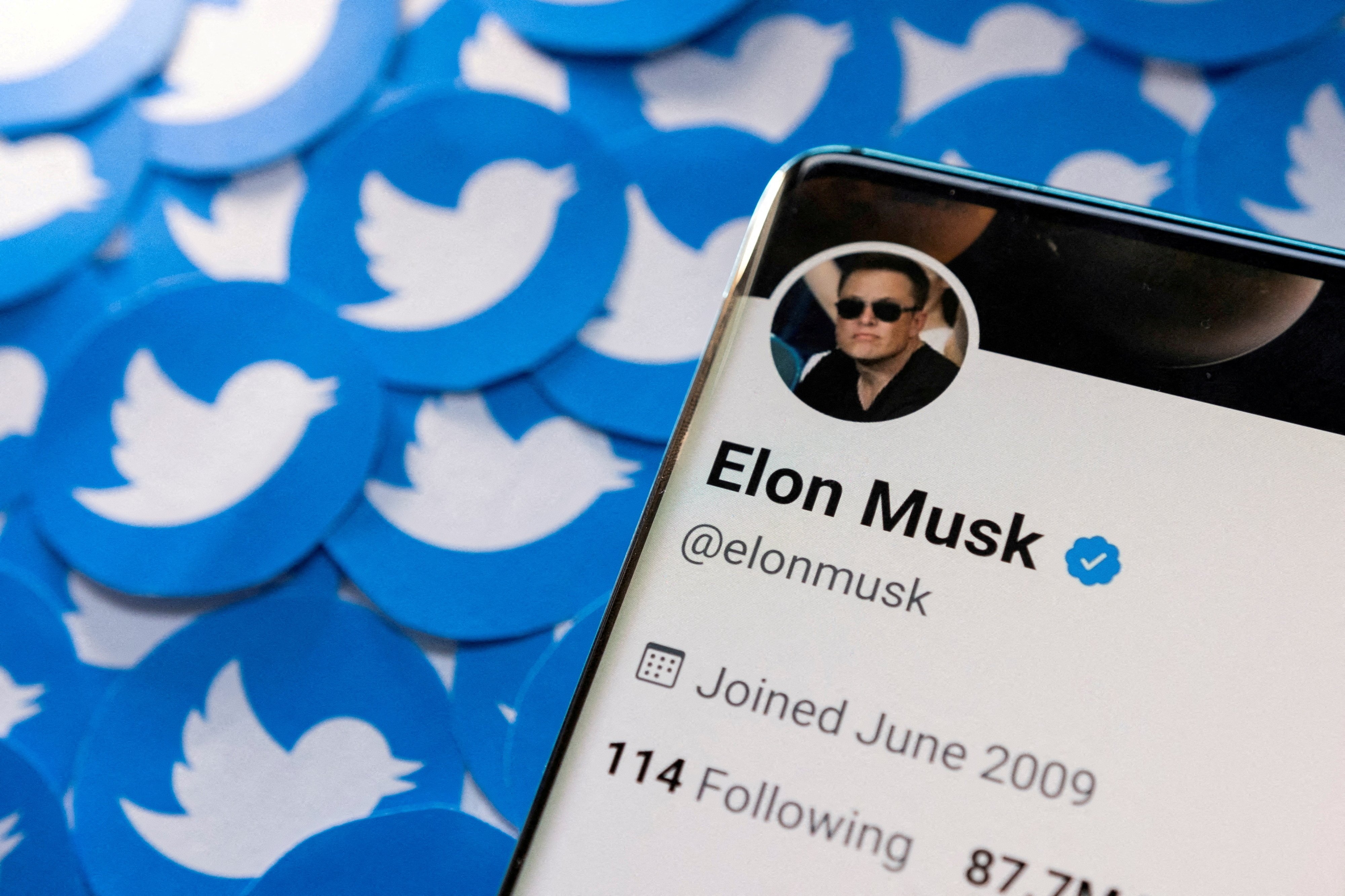 Elon Musk&#039;s Twitter profile is seen on a smartphone placed on printed Twitter logos in this picture illustration, April 28, 2022. (REUTERS File Photo)