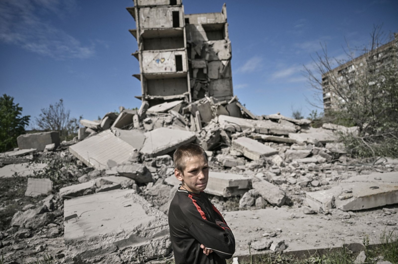 A young boy stands in front of a damaged building after a strike in Kramatorsk in the eastern Donbass region, Ukraine, May 25, 2022. (AFP Photo)