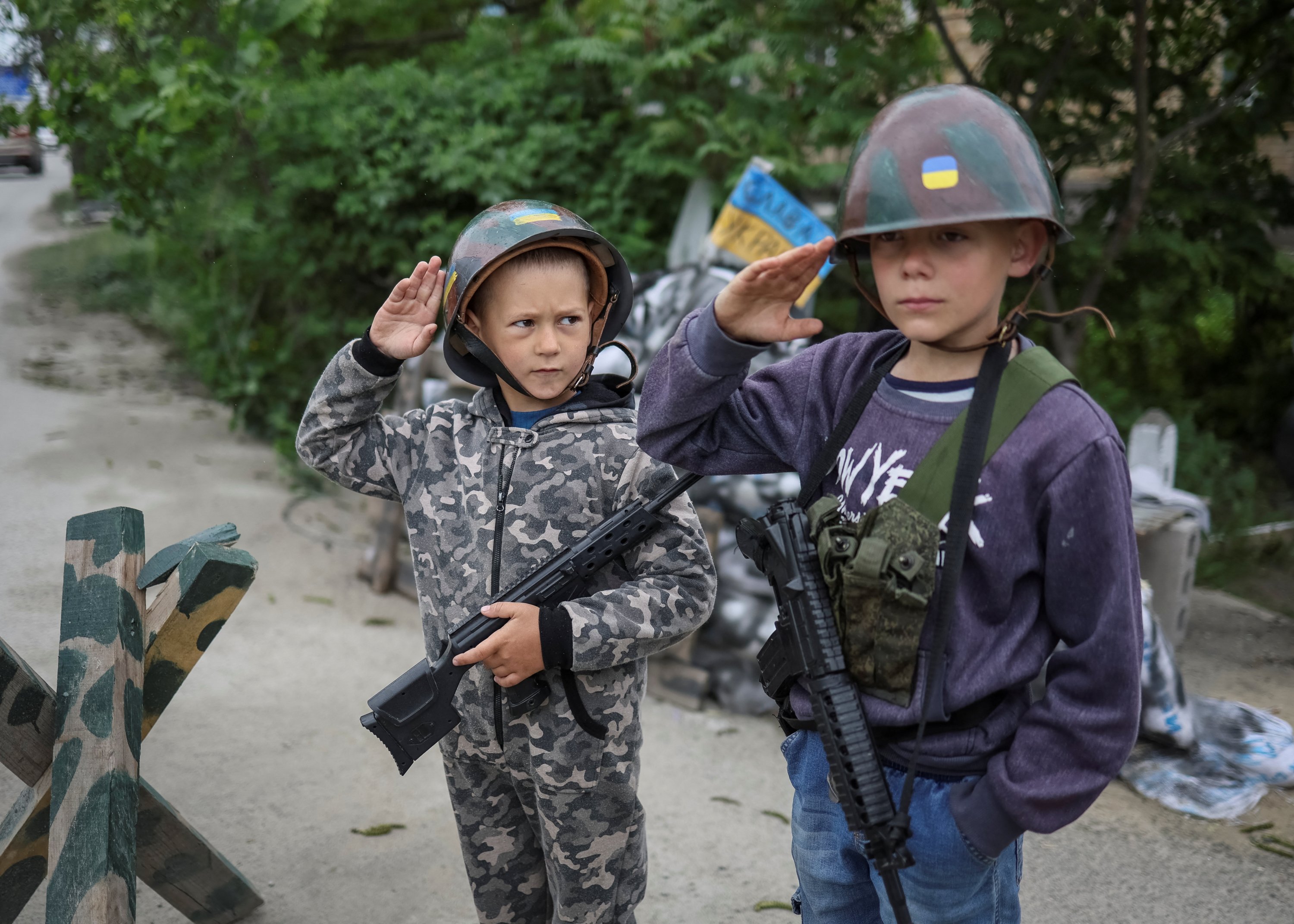 Anak-anak Ukraina Andrii, 12, dan Valentyn, 6, memberi hormat saat mereka bermain militer Ukraina di dekat rumah mereka, di tengah invasi Rusia, di desa Stoianka, di wilayah Kyiv, Ukraina 22 Mei 2022. (Foto Reuters)