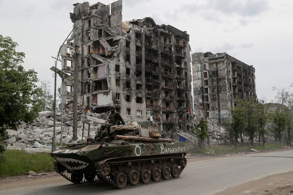 Service members of pro-Russian troops drive an armored vehicle along a street past a destroyed residential building in Popasna, the Luhansk region, Ukraine, May 26, 2022. (Reuters Photo)