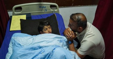 A relative checks on Sipan Farhad, a 9-year-old wounded following a rocket attack in the Kurdistan Regional Government (KRG) of Iraq, at a hospital in the northern Iraqi city of Dohuk, May 26, 2022. (AFP Photo)