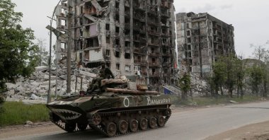 Service members of pro-Russian troops drive an armored vehicle along a street past a destroyed residential building in Popasna, the Luhansk region, Ukraine, May 26, 2022. (Reuters Photo)