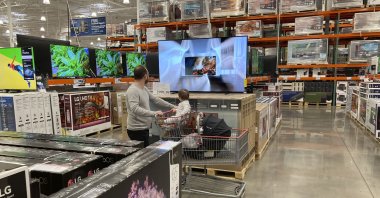 A shopper pushes a child in a cart while browsing big-screen televisions on display in the electronics section of a Costco warehouse in Lone Tree, Colo. U.S., March 29, 2022 (AP Photo)