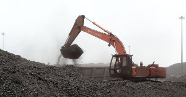 A worker uses an excavator to load coal onto a truck in the vicinity of the Deendayal Port Authority seaport at Kandla in India's Gujarat state, May 18, 2022. (AFP Photo)