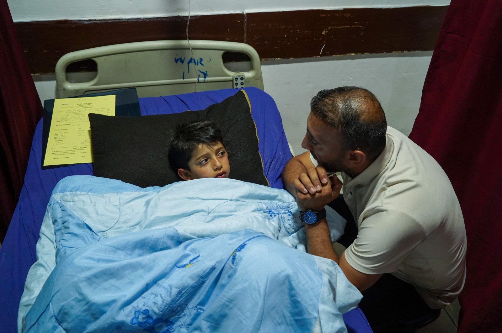 A relative checks on Sipan Farhad, a 9-year-old wounded following a rocket attack in the Kurdistan Regional Government (KRG) of Iraq, at a hospital in the northern Iraqi city of Dohuk, May 26, 2022. (AFP Photo)