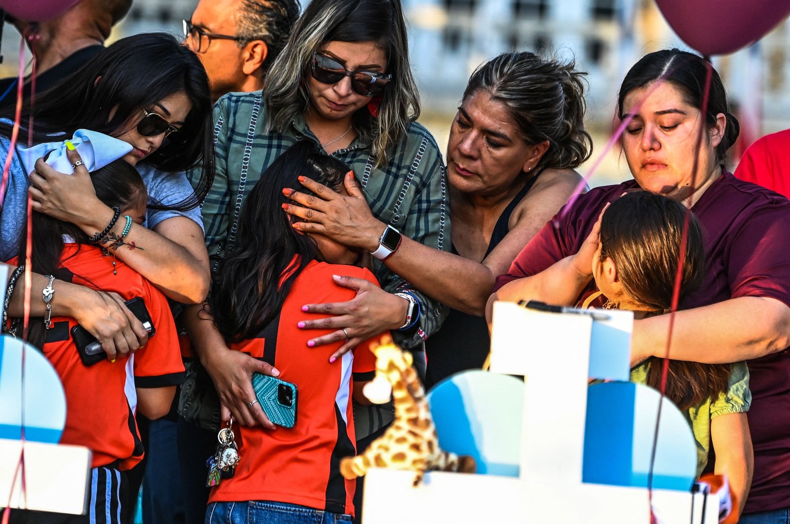 Soccer teammates of Tess Mata, who died in Texas shooting, cry, supported by their mothers, as they visit a makeshift memorial outside the Uvalde County Courthouse in Texas, U.S., May 26, 2022. (AFP Photo)