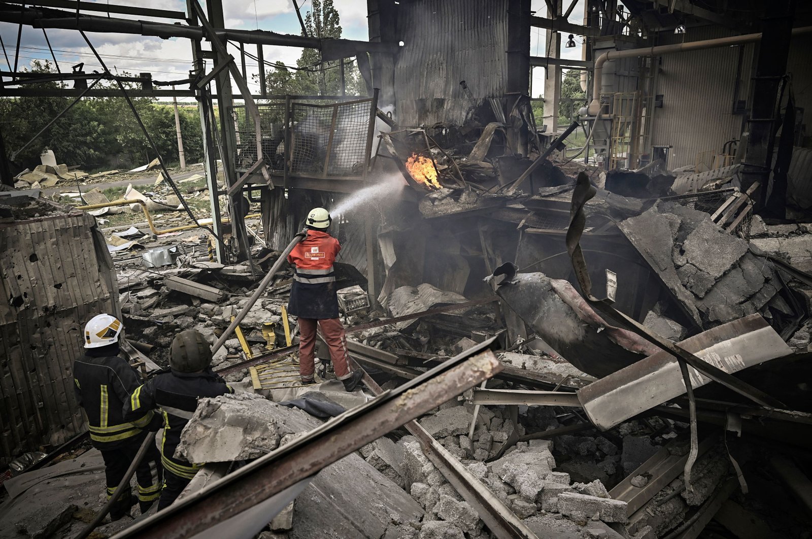 Firemen extinguish a fire at a Gypsum Manufactory plant after shelling in the city of Bakhmut at the eastern Ukrainian region of Donbas on May 27, 2022, on the 93rd day of the Russian invasion of Ukraine. - Russia on May 27, 2022 pressed its deadly offensive to capture key points in the eastern Donbas region of Ukraine, with more bombing of residential areas and pro-Moscow forces claiming the capture of a key town on the way to Kyiv-controlled territory. (Photo by Aris Messinis / AFP)