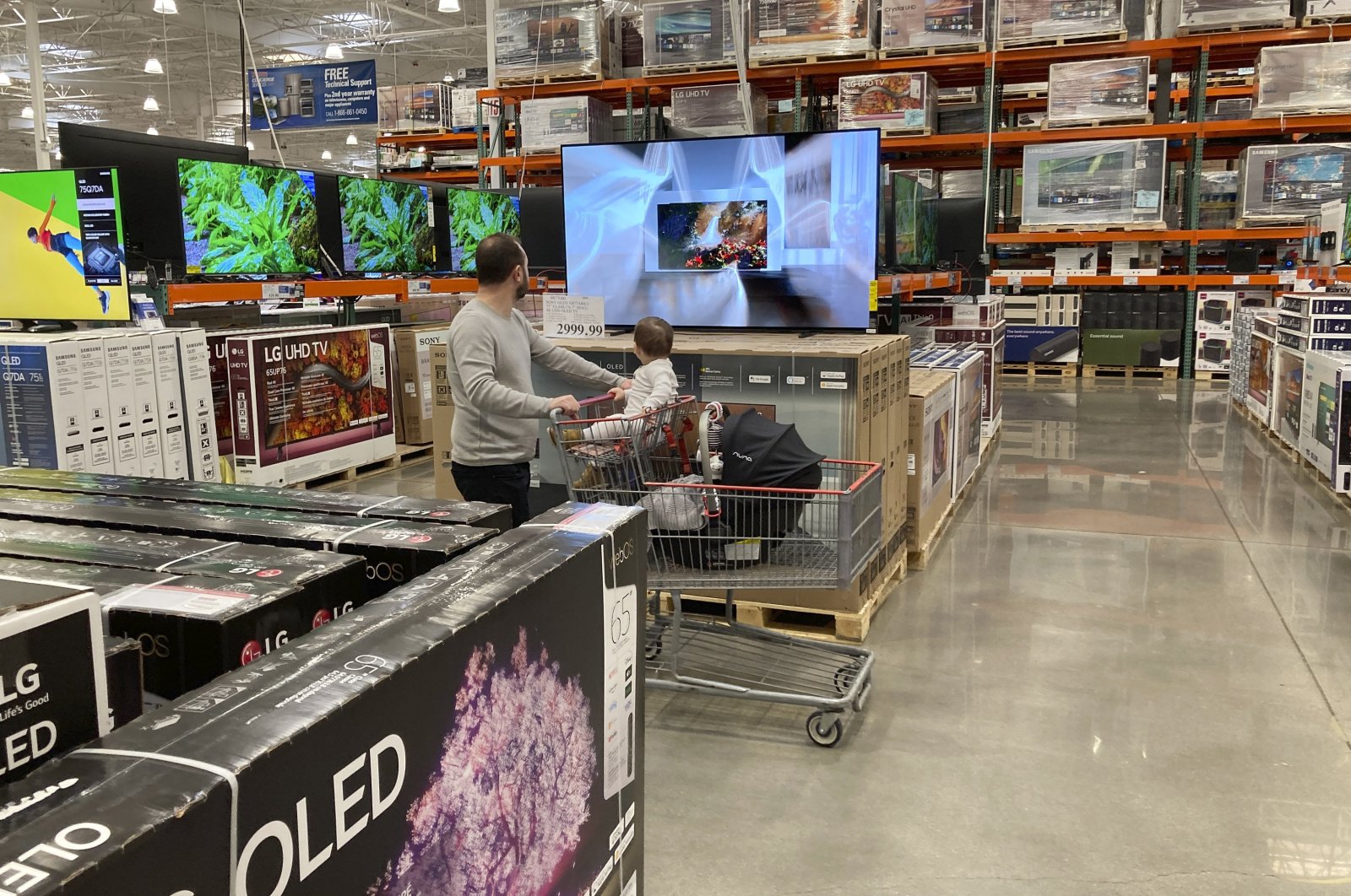 A shopper pushes a child in a cart while browsing big-screen televisions on display in the electronics section of a Costco warehouse in Lone Tree, Colo. U.S., March 29, 2022 (AP Photo)