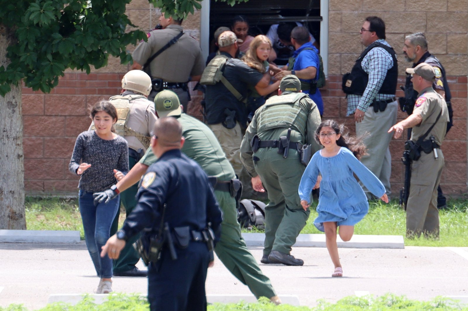 Children run to safety after escaping from a window during a mass shooting at Robb Elementary School where a gunman killed 19 children and two adults in Uvalde, Texas, U.S., May 24, 2022. (Uvalde Leader-News via Reuters)
