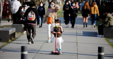 A girl wearing a protective face mask to prevent contracting the coronavirus rides a toy kick scooter at a park in Seoul, South Korea, April 3, 2020. (Reuters Photo)