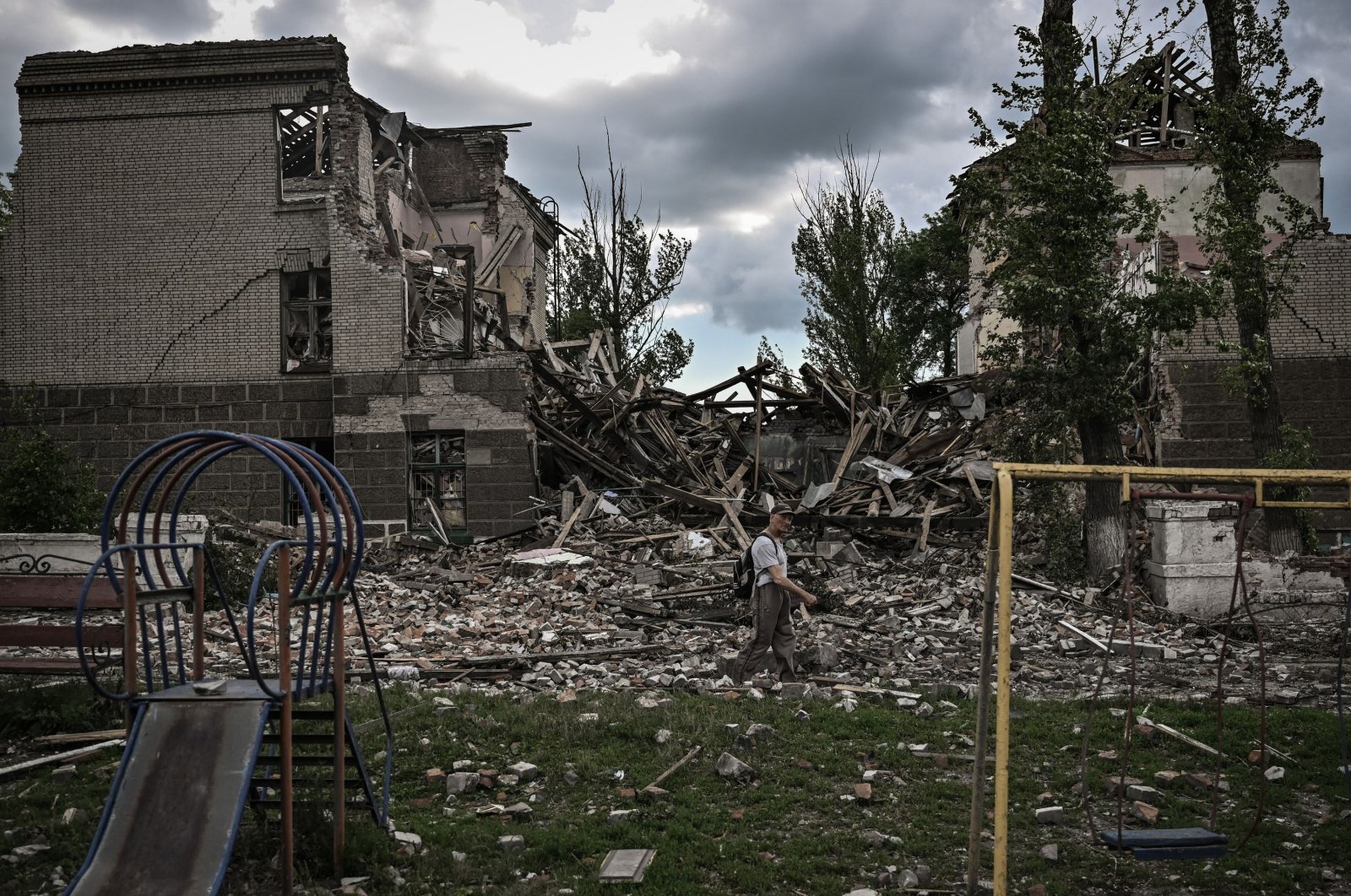 A man walks in front of a destroyed school in the city of Bakhmut amid the Russian invasion of Ukraine, Donbass region, eastern Ukraine, May 28, 2022. (AFP Photo)