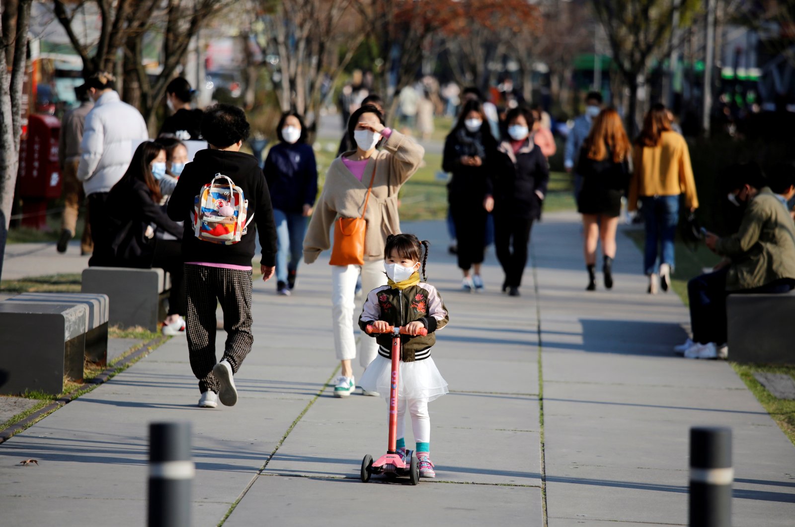 A girl wearing a protective face mask to prevent contracting the coronavirus rides a toy kick scooter at a park in Seoul, South Korea, April 3, 2020. (Reuters Photo)