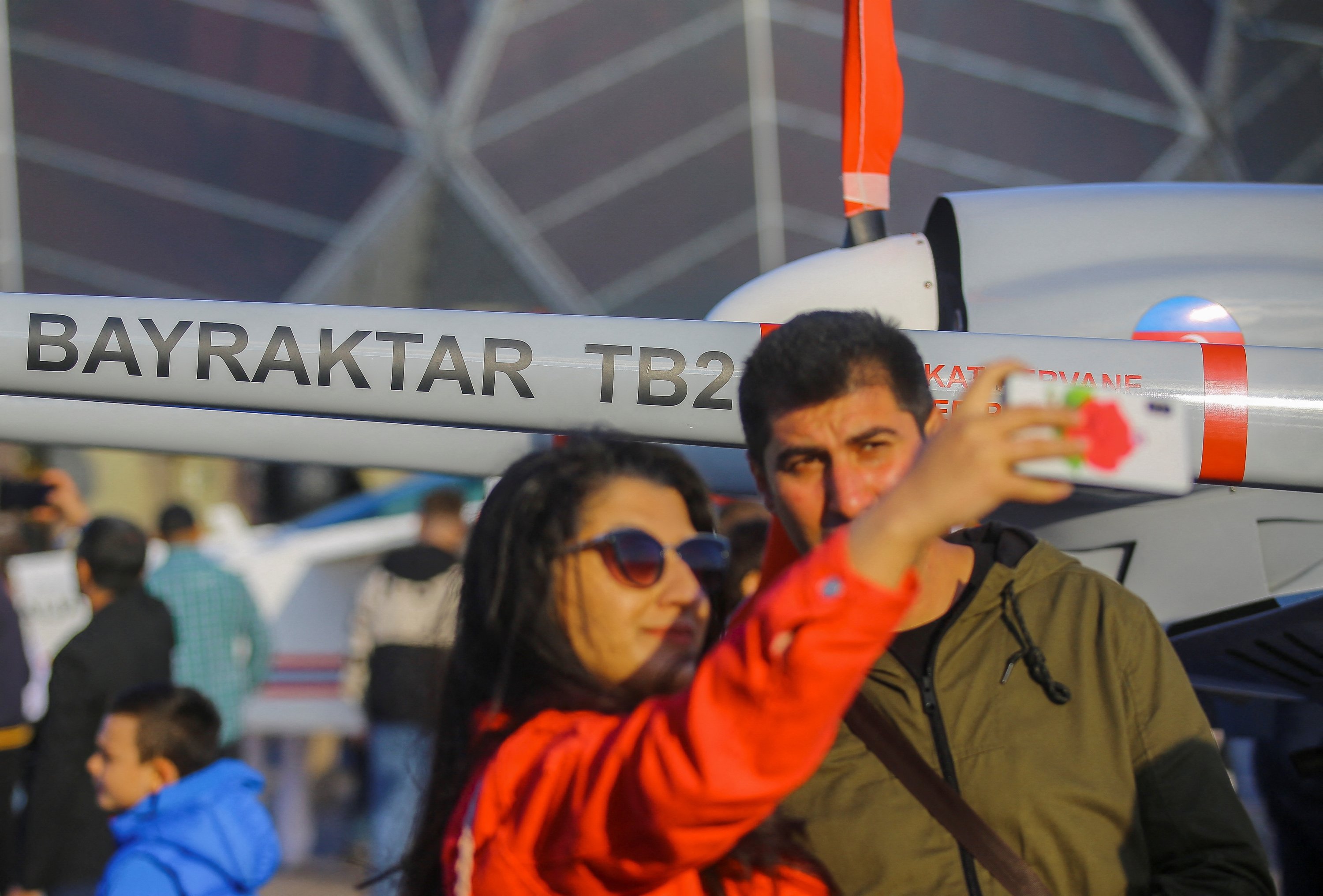 People pose for a picture in front of a Bayraktar TB2 unmanned combat aerial vehicle at the Teknofest aerospace and technology festival in Baku, Azerbaijan, May 27, 2022. (Reuters Photo)