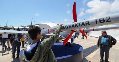 A young man looks at a Bayraktar TB2 drone, manufactured by Turkey's Baykar, as it is presented during the opening of the aerospace and technology festival Teknofest Azerbaijan at Baku Crystal Hall in Baku, Azerbaijan, May 27, 2022. (AFP Photo)