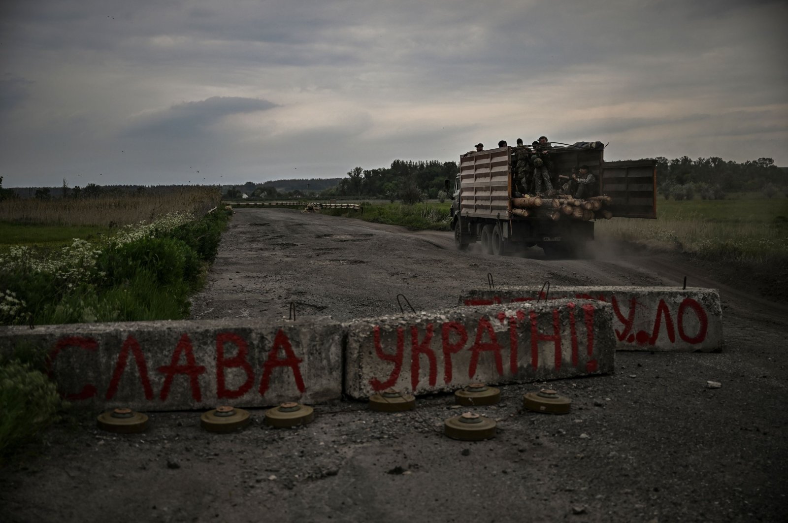 A truck with Ukrainian officers drives by a roadblock, with ant-tank mines, inscribed “Glory to Ukraine” outside the city of Barvinkove in the eastern Donbass region, Ukraine, May 29, 2022. (AFP Photo)