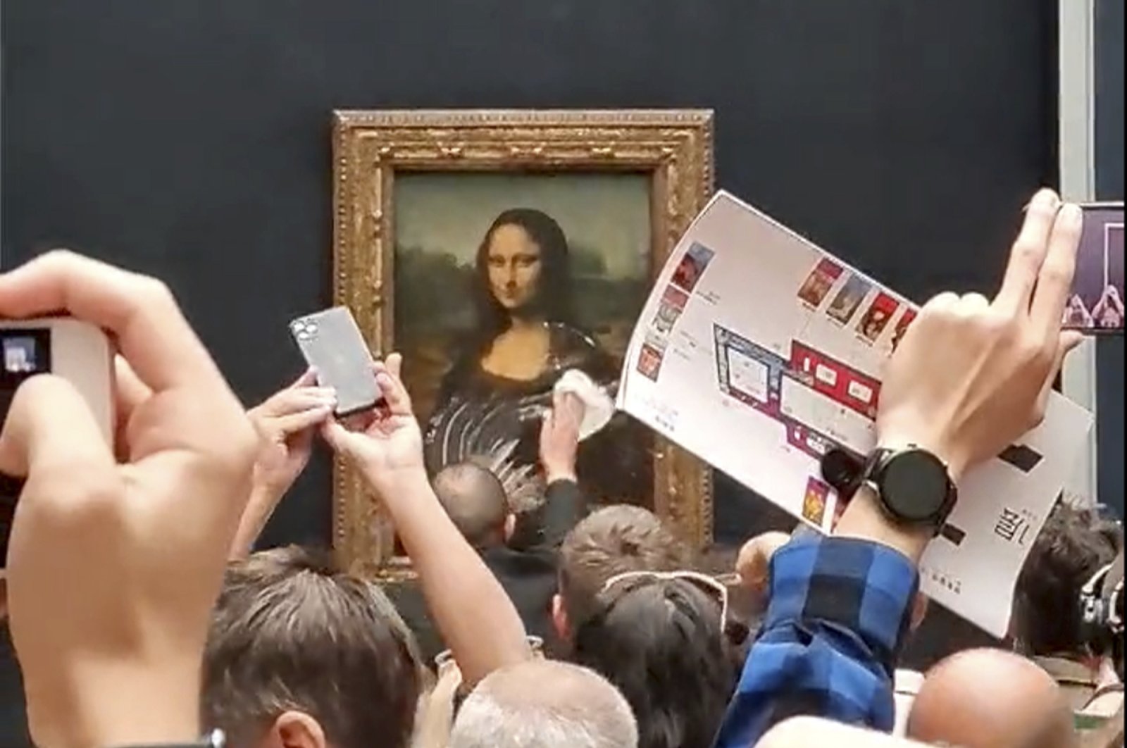 A security guard cleans the smeared cream from the glass protecting the Mona Lisa at the Louvre Museum, in Paris, France, May 29, 2022. (AP Photo)