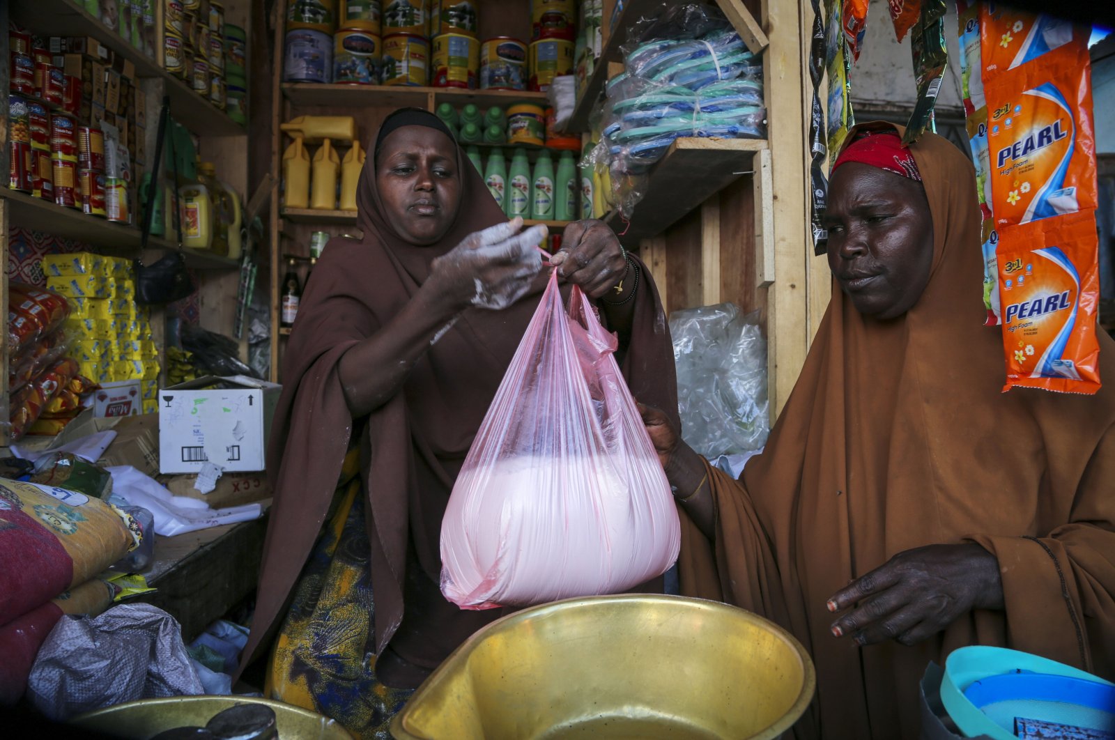 Halimo Hersi, 42, right, buys wheat flour from a shopkeeper in the Hamar-Weyne market in the capital Mogadishu, Somalia, May 26, 2022. (AP Photo)