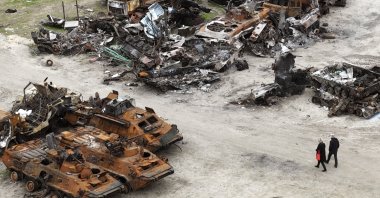 People walk past wrecks of military vehicles in Bucha, on the outskirts of Kyiv, Ukraine, April 30, 2022. (AP Photo)
