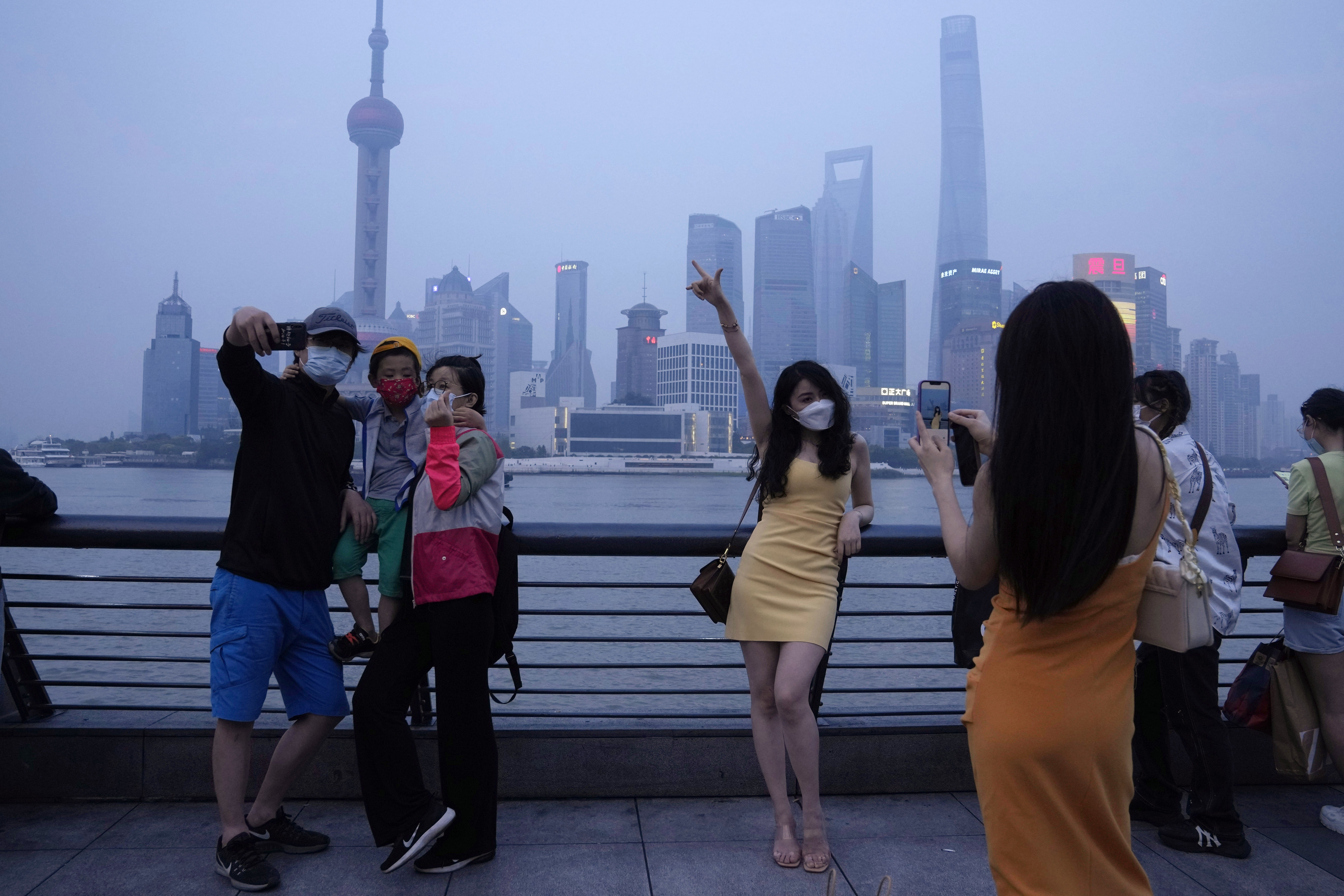 Residents pose for photos along the bund in Shanghai amid the easing of a strict two-month COVID-19 lockdown, China, June 1, 2022. (AP Photo)