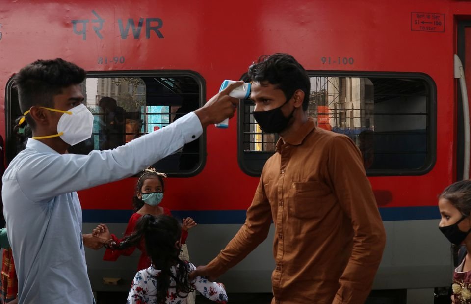 A health care worker checks the temperature of a passenger upon his arrival at a railway station, Mumbai, India, Nov. 29, 2021. (Reuters Photo)
