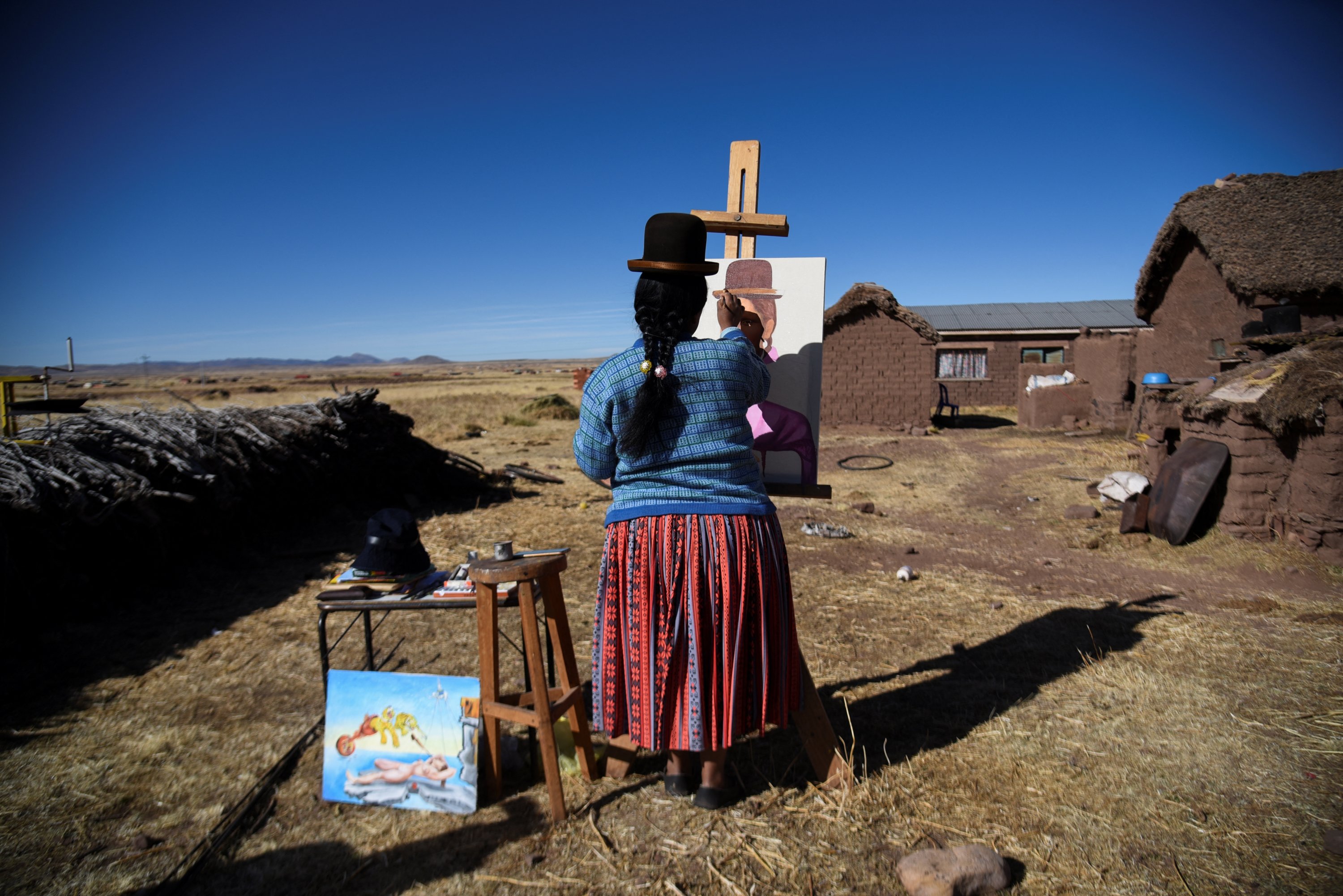 Claudia Callizaya, 32, seorang pelukis Bolivia yang dikenal sebagai Claudina, memberikan sentuhan akhir pada lukisan Mona Lisa gaya cholita-nya, di rumahnya di Kalla Baja, Bolivia, 29 Mei 2022. (Foto Reuters)