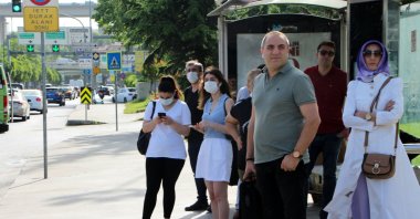 People with and without COVID-19 masks wait at a bus stop, in Istanbul, Turkey, May 30, 2022. (DHA PHOTO) 